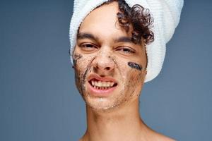 söt kille med en handduk på hans huvud ansikte grädde hud vård foto