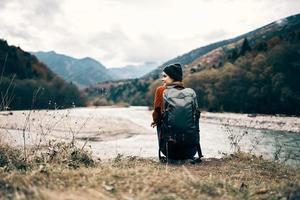 kvinna resande med en ryggsäck på henne tillbaka gester med henne händer och utseende på de bergen i de distans foto