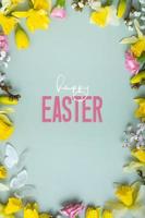 Lycklig påsk text med vår blommor platt lägga ram sammansättning på färgad bakgrund. vertikal påsk hälsning kort foto