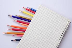 Graf bok med färgad pennor eller pastell fodrad upp på vit bakgrund. inlärning, studie och presentation begrepp. foto