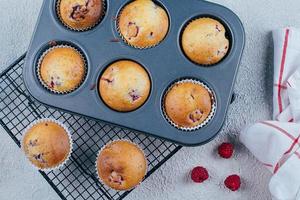 bakad hallon muffins på en kyl- kuggstång på blå betong tabell bakgrund. frukost begrepp foto