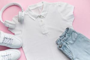 barnets t-shirt, skor och hörlurar på rosa bakgrund foto