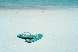 närbild par gamla sandaler på den vita sandstranden foto