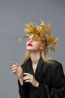 glamorös kvinna gyllene löv på de huvud i svart jacka studio modell oförändrad foto
