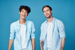 Lycklig vänner i identisk shirts chattar på en blå bakgrund roligt modell foto