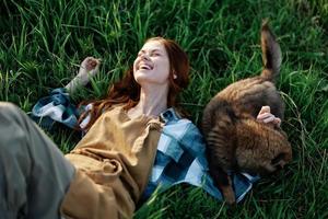 en kvinna lögner på de gräs leende och kel henne hund i natur i en parkera i de sommar solnedgång. de begrepp av hälsa och kärlek för djur, behandling mot fästingar foto