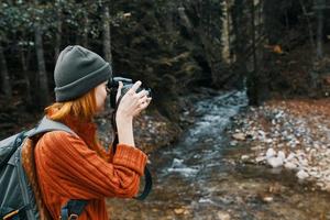kvinna med en kamera på natur i de bergen nära de flod och lång träd skog landskap foto