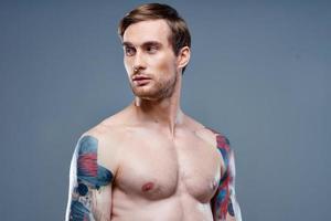 man med tatuering naken torso sport kondition grå bakgrund porträtt foto