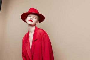 glamorös kvinna röd jacka och hatt röd mun mode beige bakgrund foto