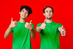 två glad vänner från grön t-tröjor gestikulera med händer känslor foto