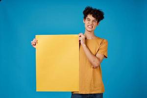kille med lockigt hår gul affisch attrapp reklam blå bakgrund foto