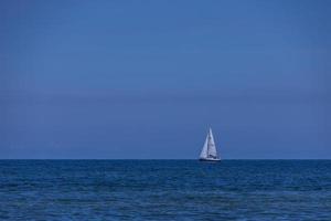 sommar landskap från de baltic hav med blå vatten och himmel och en vit segelbåt foto