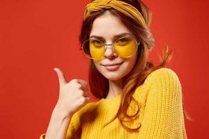 kvinna i gul glasögon med en bandage på henne huvud gul Tröja hipster röd bakgrund foto