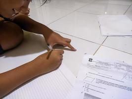en tonåring är skrivning på papper för läxa foto