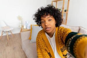 Lycklig afrikansk amerikan tonåring flicka bloggare leende ansikte talande till webbkamera inspelning vlogg. social media influencer kvinna strömning framställning video ring upp på Hem. huvudskott porträtt selfie webbkamera se. foto