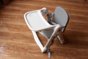 bebis hög stol på en trä mönster golv. bebis Utrustning begrepp. foto