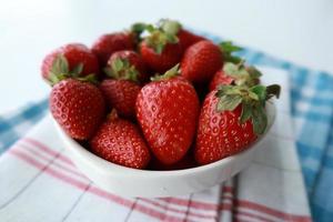 mogen röd jordgubbar i en skål på tabell foto