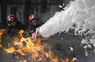 brandmän släcka en brand. livräddare med brand slangar i rök och brand. foto