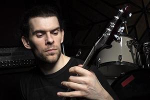 en man spelar de gitarr. ansikte av en man med en musikalisk instrument på en mörk bakgrund. foto