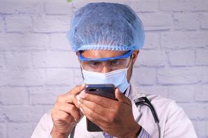 läkare i skyddsmask med smartphone på sjukhuset