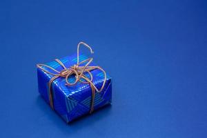 blå gåva låda bunden med ett orange rep på en blå bakgrund. foto