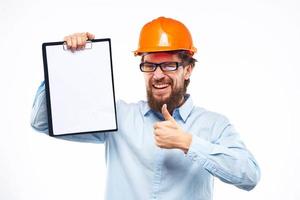en man i ett orange hård hatt med dokument industriell aktivitet arbete foto