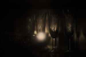 glasögon stå i mörk. ljus på glas. porslin för alkohol. foto