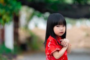 porträtt skön asiatisk liten flicka i Cheongsam klänning, thailand människor, glada kinesisk ny år koncept, glad liten asiatisk flicka i kinesisk traditionell klänning foto