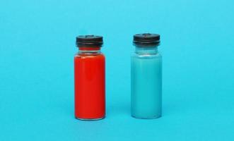 två medicinsk glas flaskor med blå och röd flytande. foto