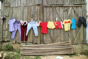 färgrik kläder hängande på en tråd på en trä- vägg. lantlig liv stil. familj begrepp foto