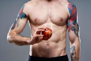 ung man med äpple och pumpade upp torso biceps man tatuering grå bakgrund beskurna se foto