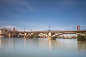 triana bro är en metall båge bro i sevilla Spanien den där ansluter de triana grannskap med de Centrum av de stad foto