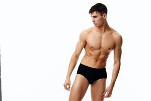 naken manlig idrottare är engagerad i kondition på en ljus bakgrund och svart trosor foto