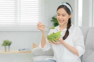 friska mat. skön kvinna flicka leende njut av äta färsk vegetabiliska sallad på frukost hälsa. Lycklig asiatisk kvinna Bra känsla. bantning, detox, diet, tappa bort vikt, rena äta, vegetarian, dietist foto