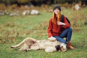 kvinna vandrare med ryggsäck gående de hund i natur äventyr foto