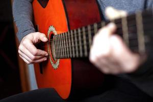 flicka som spelar en akustisk gitarr foto