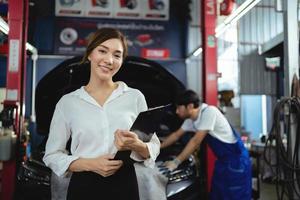 porträtt asiatisk kvinna klienter kontroll vård tjänster och reparera bilar i bil reparera garage foto