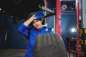 porträtt en underhåll tekniker inspekterande däck i de garage och förändra legering däck i de garage. bil underhåll. bil reparera och underhåll begrepp foto