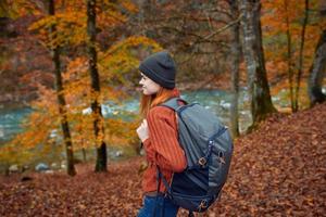 kvinna vandrare promenader i de skog i höst i natur nära de flod och löv landskap foto