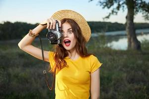 överraskad kvinna med kamera gul t-shirt hatt sommar natur livsstil foto