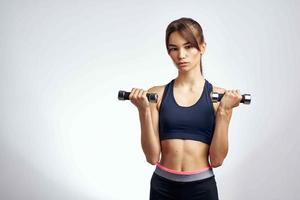 sportigt kvinna med hantlar i händer pumpade upp Tryck kondition övning Gym foto