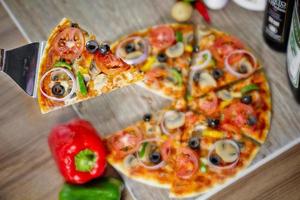 populär färgrik Ingredienser som tycka om tomater, ost, svamp, spansk peppar, oliver och Övrig Ingredienser bakad friska pizza. foto