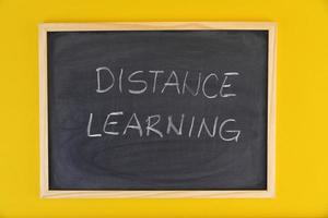 handritad titel distansutbildning på svart tavla bland gul levande bakgrund. foto