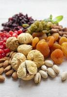 olika torkade frukter och nötter på en träbakgrund foto