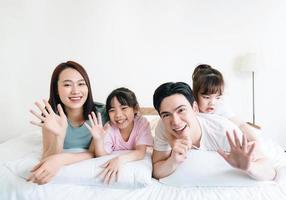 ung asiatisk familj på säng foto