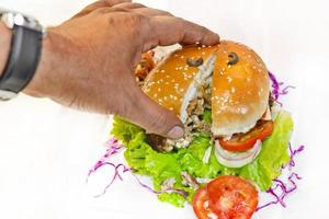 ett stor storlek burger har varit dividerat in i två pices med en hand. foto