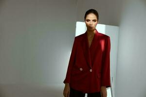 glamorös brunett i en röd jacka Framställ mot en mörk bakgrund foto