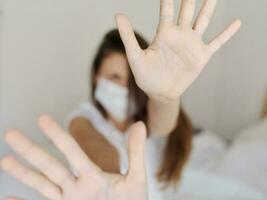emotionell kvinna i medicinsk mask omslag henne ansikte med händer aggression irritabilitet pandemi karantän foto