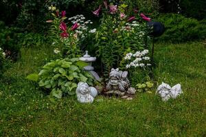 grön trädgård med blommor och plåster statyett naturlig bakgrund foto