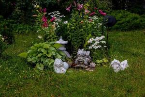grön trädgård med blommor och plåster statyett naturlig bakgrund foto